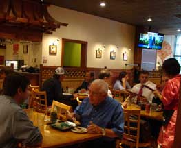 Image of attractive, busy dining room in Chiu's Sushi Japanese Restaurant with server in traditional  attire serving delicious mouthwatering sushi and other authentic Japanese dishes, Harbor East Baltimore MD