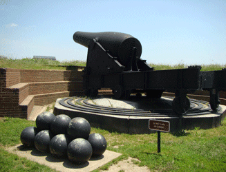 Image of large rotatable cannon on tracks with cannon balls in foreground at Fort McHenry Baltimore MD 