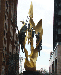 Close-up view of golden Katyn Memorial framed by Harbor East highrise buildings Baltimore MD