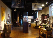 Image of the Maritime Museum in the Fell's Point Visitor Center showing exhibits including a ships wheel, paintings of historic sailboats, a model ship, displays and a work station, on historic Thames Street Baltimore, MD